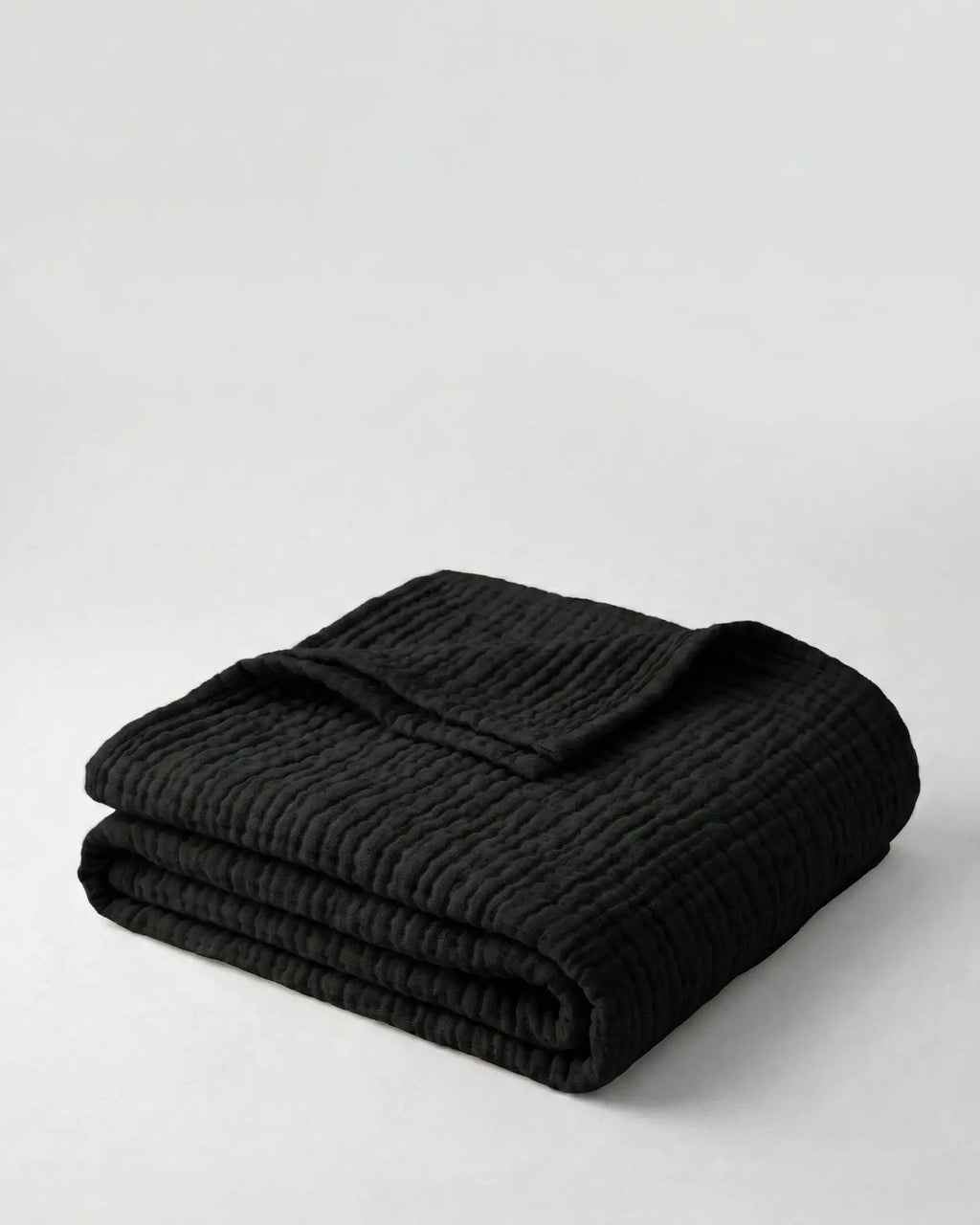 Muslin Blanket in Black draped over a bed
