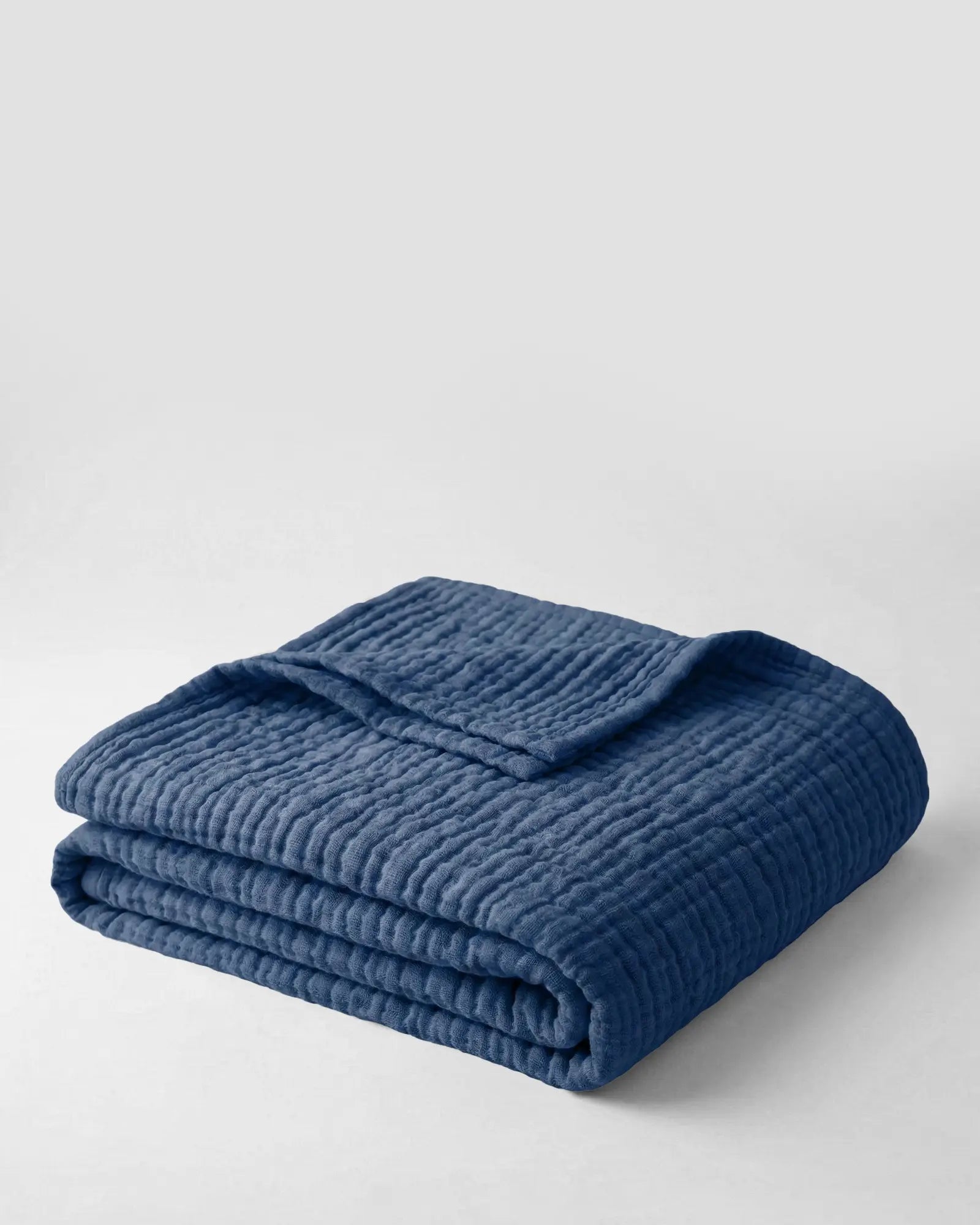 Muslin Blanket in Blue draped over a bed