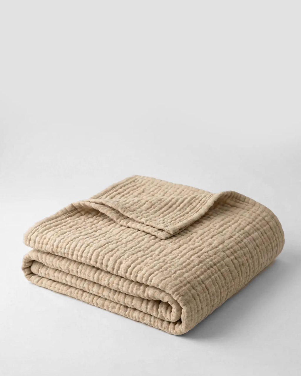 Muslin Blanket in Dune draped over a bed