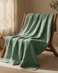 Muslin Blanket in Green in a bedroom