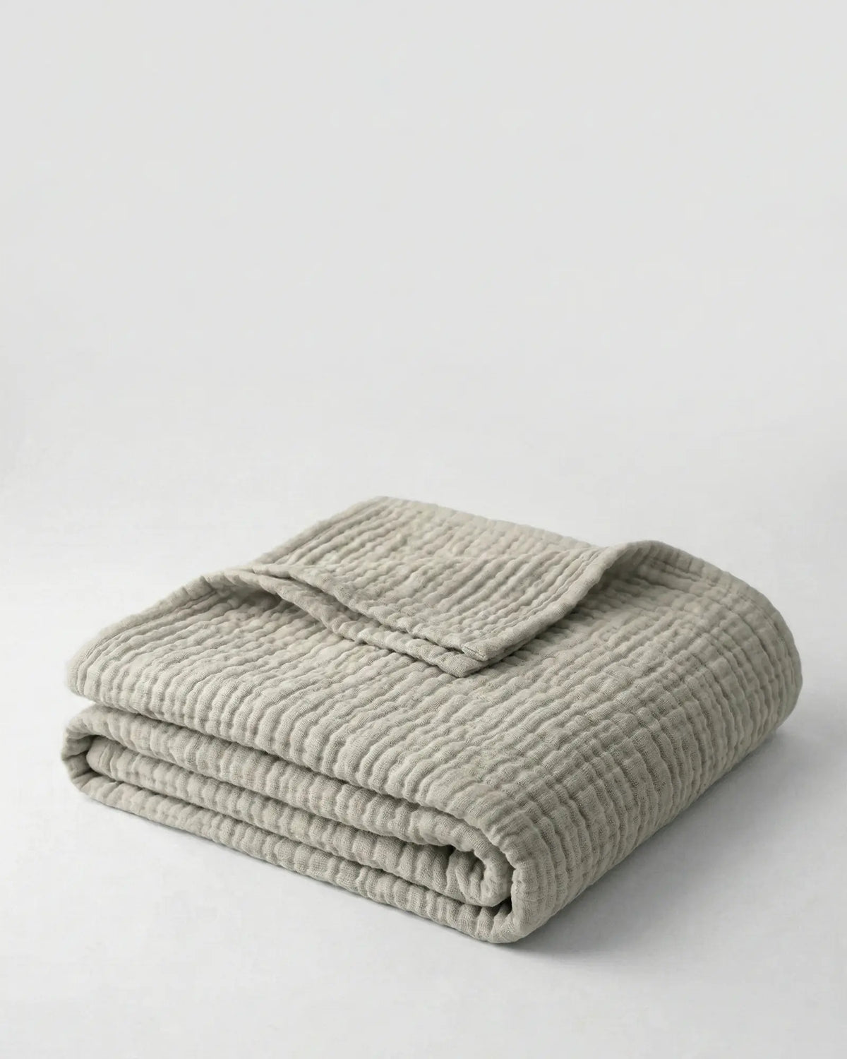 Muslin Blanket in Grey draped over a bed
