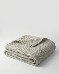 Muslin Blanket in Grey draped over a bed