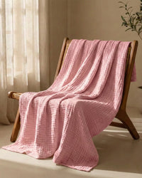 Muslin Blanket in Pink in a bedroom