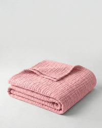 Muslin Blanket in Pink draped over a bed