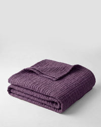 Muslin Blanket in Purple draped over a bed