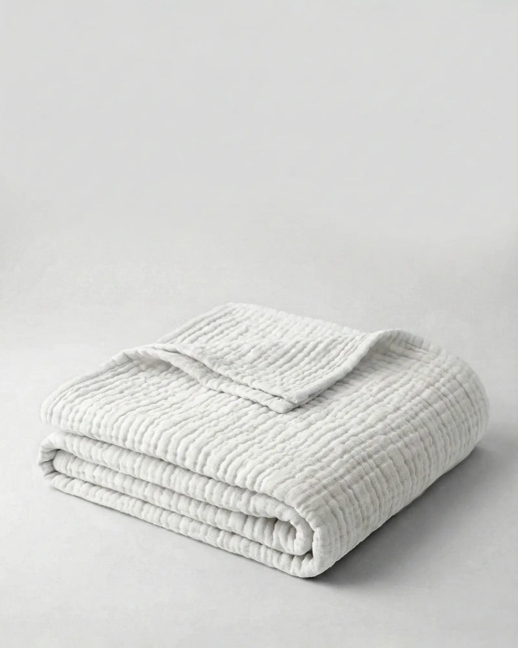 Muslin Blanket in White draped over a bed