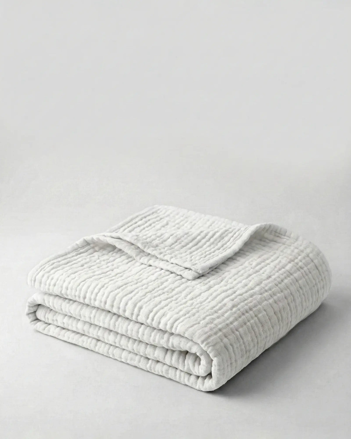 Muslin Blanket in White draped over a bed